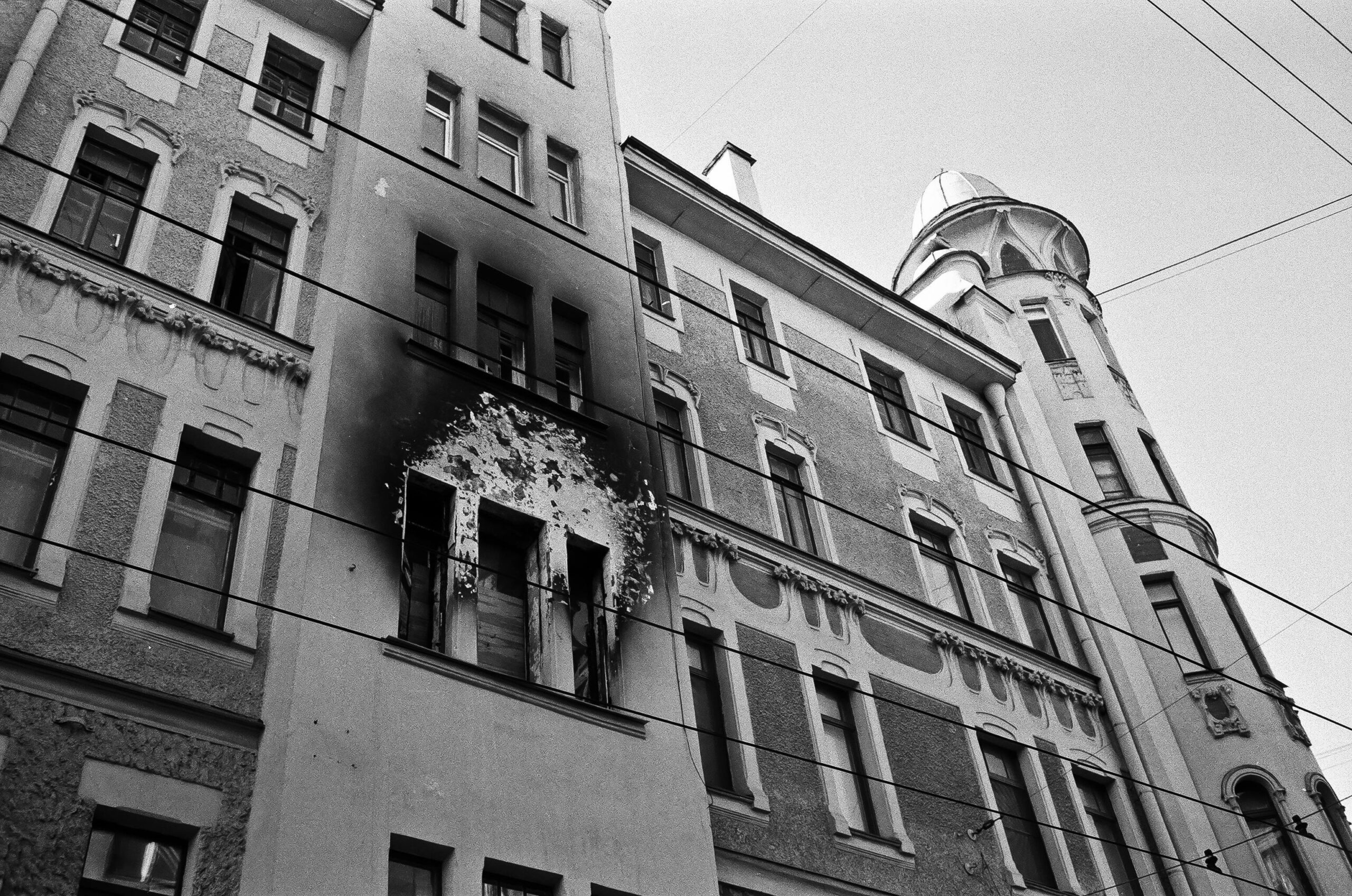 Black and white of exterior of aged residential building with dirty windows and walls after fire placed in city in daytime